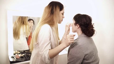 Young makeup artist applying base to the young woman's face Stock Footage 75381851