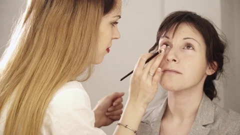 Young makeup artist applying base with brush to the face Stock Footage 75381930