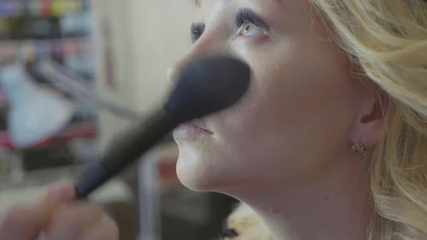 Young makeup artist applying concealer on model's face. Stock Footage 82379412