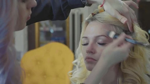 Young makeup artist applying concealer on model's face. Stock Footage 82386664