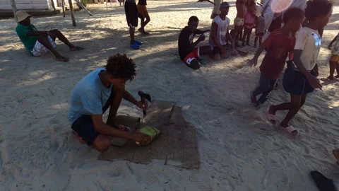 Young Malagasy man cutting coconut with hatchet for tourists in local village Stock Footage 308809083