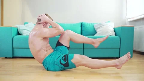 Young male athlete bodybuilder doing crisscross physical exercises at home  Stock Footage 143756256