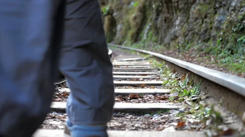 Young male backpacker is going on train rail alone, rear view Stock Footage 119696840