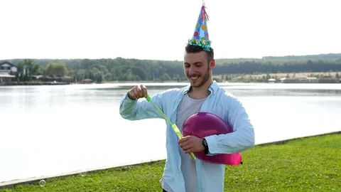 Young male with a birthday cap on the lake background. Stock Footage