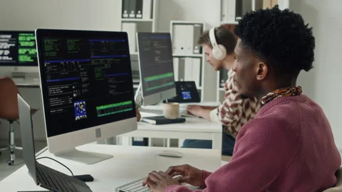 Young Male Black Programmer Coding on Computer next to Colleague in Office Stock Footage 330128223
