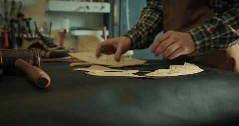 Young male bootmaker putting patterns on table for new project at the workshop. Video stock 246307196