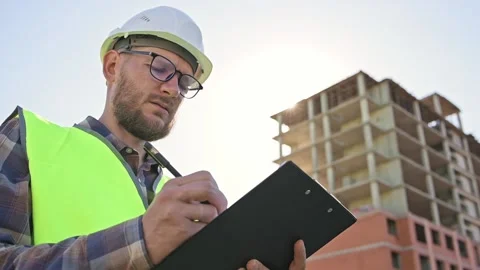 Young male builder engineer architect foreman designer holds black folder in Stockbeeldmateriaal 204842439