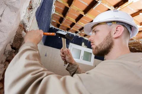 Young male builder using hammer chisel Foto stock