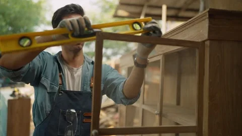 Young male carpenter using precision level making new furniture at wood workshop Stock Footage 264287398