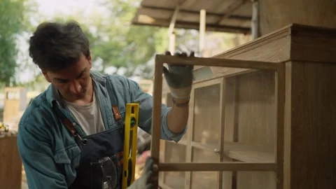 Young male carpenter using precision level making new furniture at wood workshop Stock-Footage 264289215