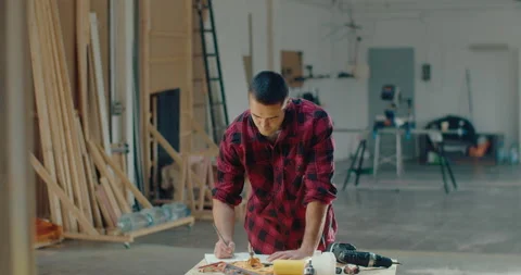 Young male carpenter working in his woodwork or workshop while writing on the Stock Footage 199614596