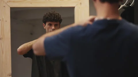 Young male choosing between jackets in front of mirror, getting ready for a date Stock Footage 341017098