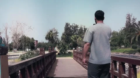Young Male Content Creator Vlogging With Smartphone On Park Bridge Видео 340400588