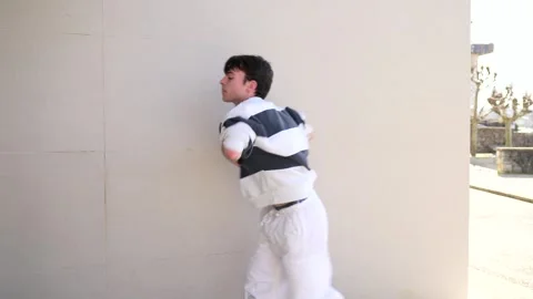 Young male dancer performing modern choreography against white wall Stock Footage 303335542