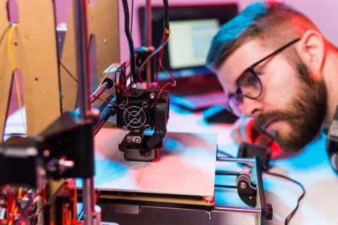 Young male designer engineer using a 3D printer in the laboratory and studying a Foto stock
