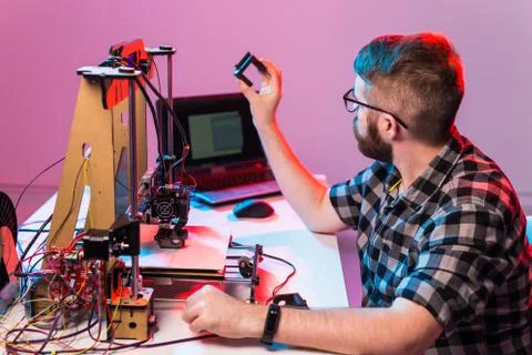Young male designer engineer using a 3D printer in the laboratory and studying a Foto stock