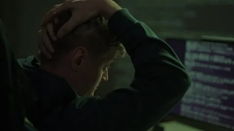Young male developer feeling stressed and overwhelmed, working late at night in Stock Footage 321685491