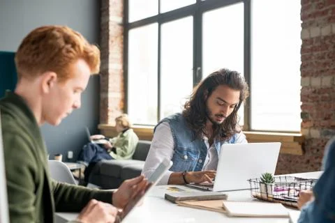 Young male developer of software working in front of laptop among co-workers Stock Photos