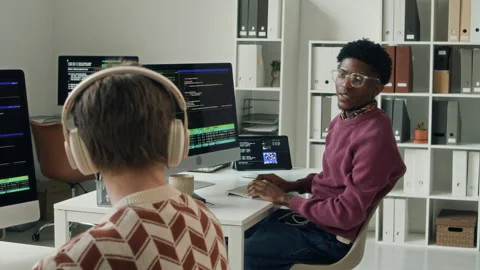 Young Male Developer Stretching Arms then Asking Colleague Question in Office Stock Footage 330126505