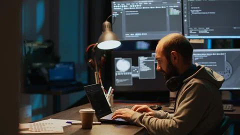 Young male developer typing server code on multiple screens Foto stock