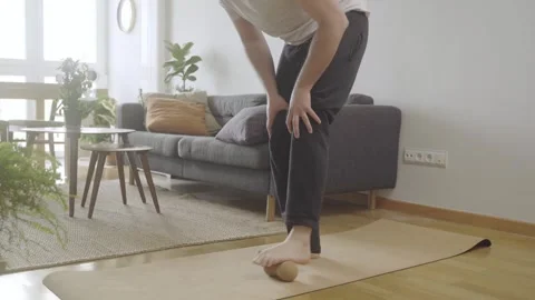 Young male doing mobility routine at home with foam rolling massage on foot Stock Footage 274500657