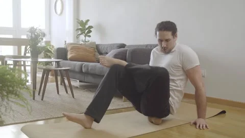 Young male doing mobility routine at home with foam rolling massage on hip Stock Footage 274500659