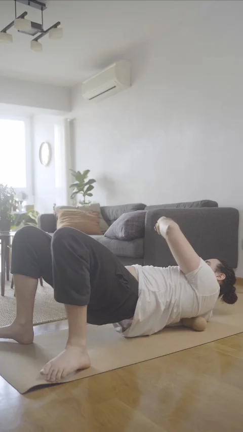 Young male doing mobility routine at home with foam rolling massage on hip Stock Footage 274500693