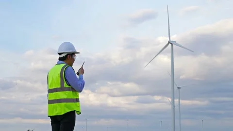 Young male engineer using walkie-talkie to checking system against wind turbine  Stock-Footage 157856373