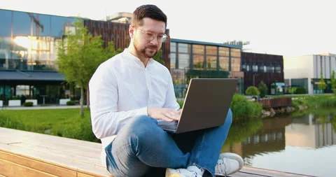 Young male freelancer working computer at modern glass building background outdo Stock Footage 316302773