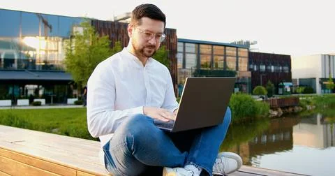 Young male freelancer working computer at modern glass building background .. Stock Photos
