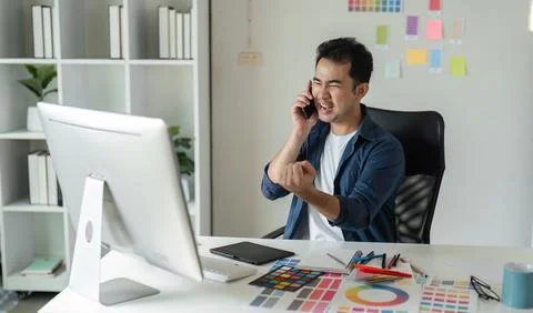 Young Male Graphic Designer Focused on Creative Project at Modern Workspace with Stock Photos