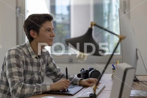 Young male graphic designer working on computer using digital tablet Stock Photos