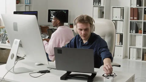 Young Male IT Engineer Stretching Arms while Coding on Laptop in Office Stock Footage 330128233