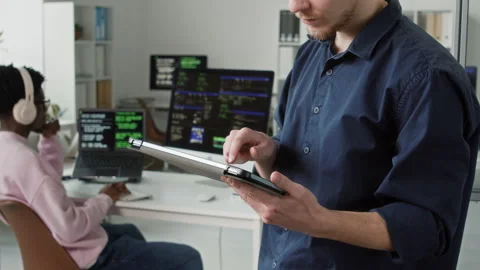 Young Male IT Programmer Typing on Tablet Screen Testing App in Office Stock Footage 330130046