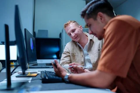 Young male IT software developer smiling while his colleague uses a pen to .. Stock-Fotos