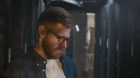 Young Male IT Specialist Analyzing Mainframe Work in Data Center Stock Footage 303555154