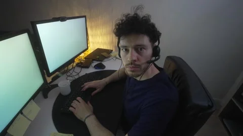 Young male looks into camera while working on computer in homely setup Stock Footage 247235110