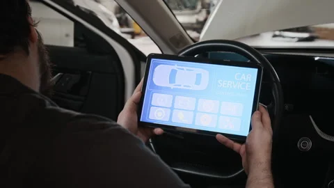 Young Male Mechanic with Tablet Testing Car Systems, Sitting at Steering Wheel Stock Footage 329410290