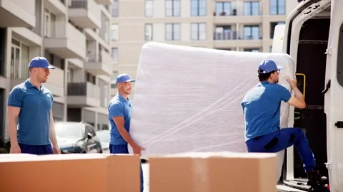 Young male movers carefully loading a wrapped mattress into a moving truck Stock Footage 278267391
