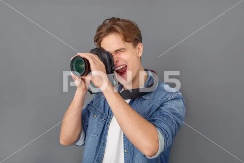 Young male photographer in jeans jacket studio isolated on grey taking pictures Stock Photos
