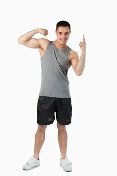 Young male pointing up while showing his biceps Stock Photos