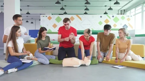 Young male practicing CPR first aid on a mannequin in the presence of people. Stock Footage 145453800
