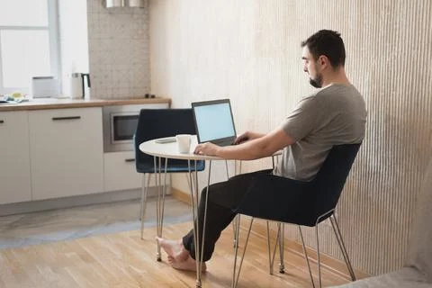Young male professional using computer sitting at home desk. Busy freelancer Stock Photos