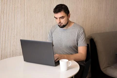 Young male professional using computer sitting at home desk. Busy freelancer Stock Photos