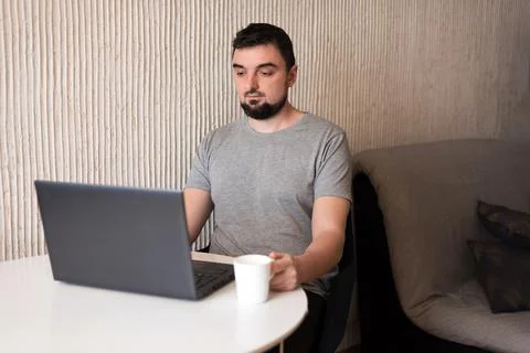 Young male professional using computer sitting at home desk. Busy freelancer Stock Photos