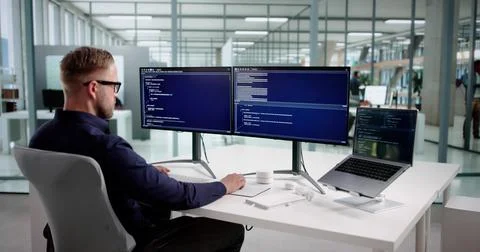 Young Male Programmer Debugging Code On Office Desktop Computer Station. Stock Photos