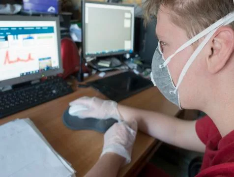 Young male programmer working at a computer in a protective mask and gloves Foto stock