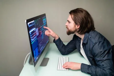 Young Male programmer working on desktop computer at white desk in office. Stockfoto's