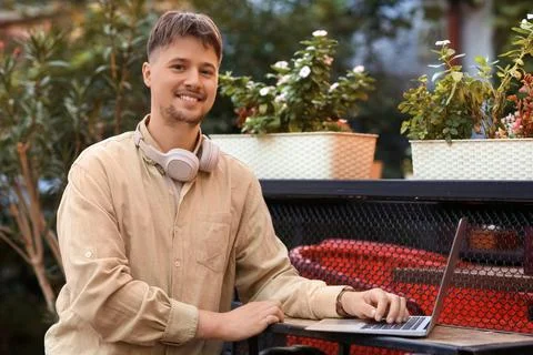 Young male programmer working with laptop at table in street cafe Stock Photos