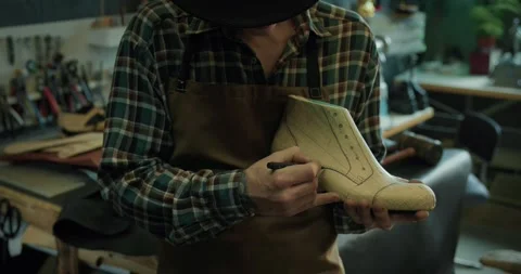 Young male shoemaker drawing pattern on a shoe last at the workshop. Video stock 246307478